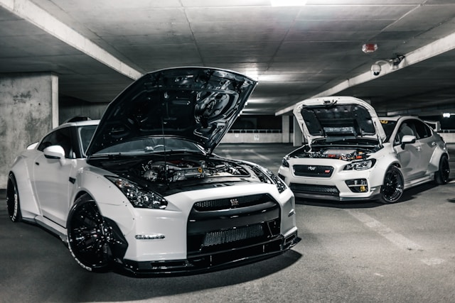 two-white-cars-with-open-hoods